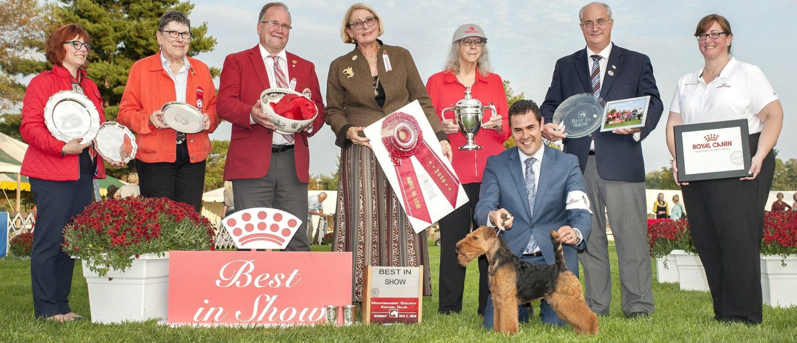 Group of people with dog and awards at a dog show.