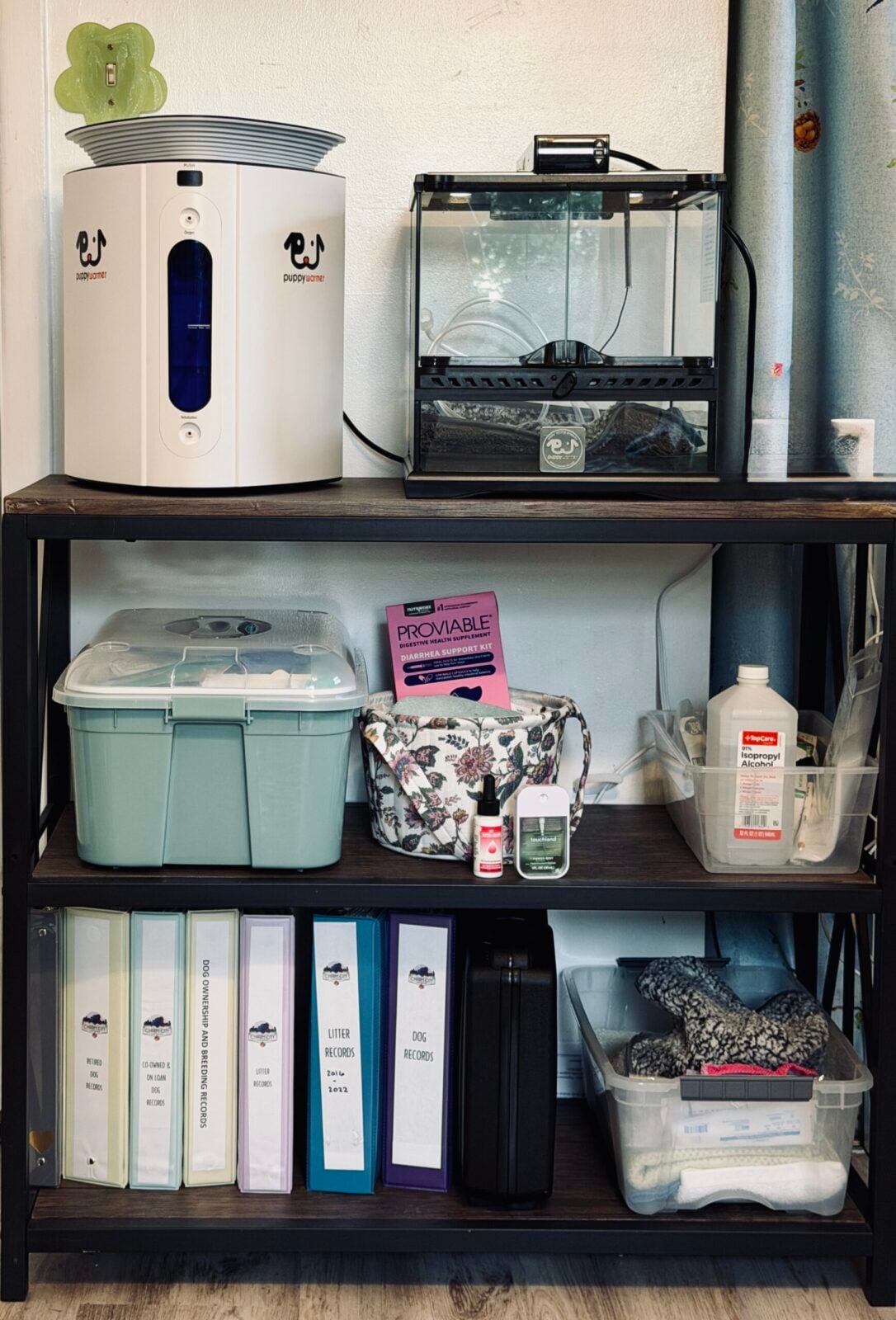 Pet supplies on shelves: white pet feeder, terrarium, storage bins, binders, and alcohol.