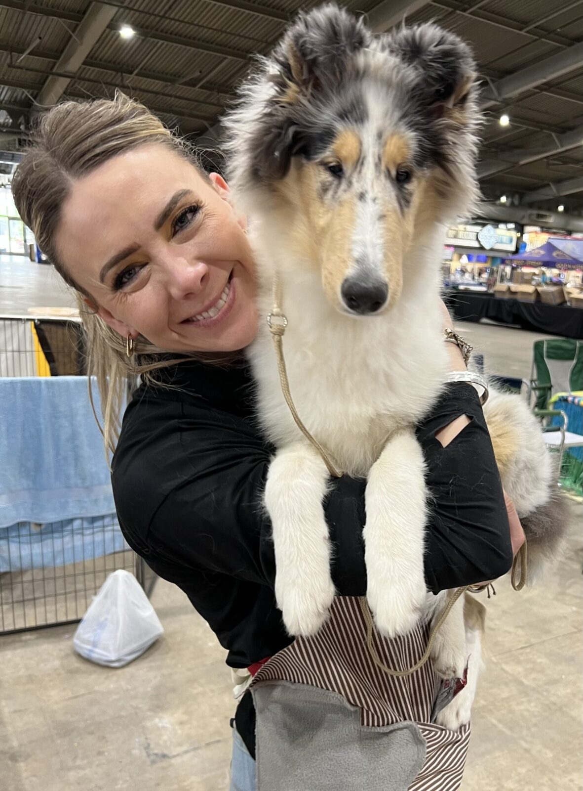 Woman holding a fluffy blue merle collie puppy.