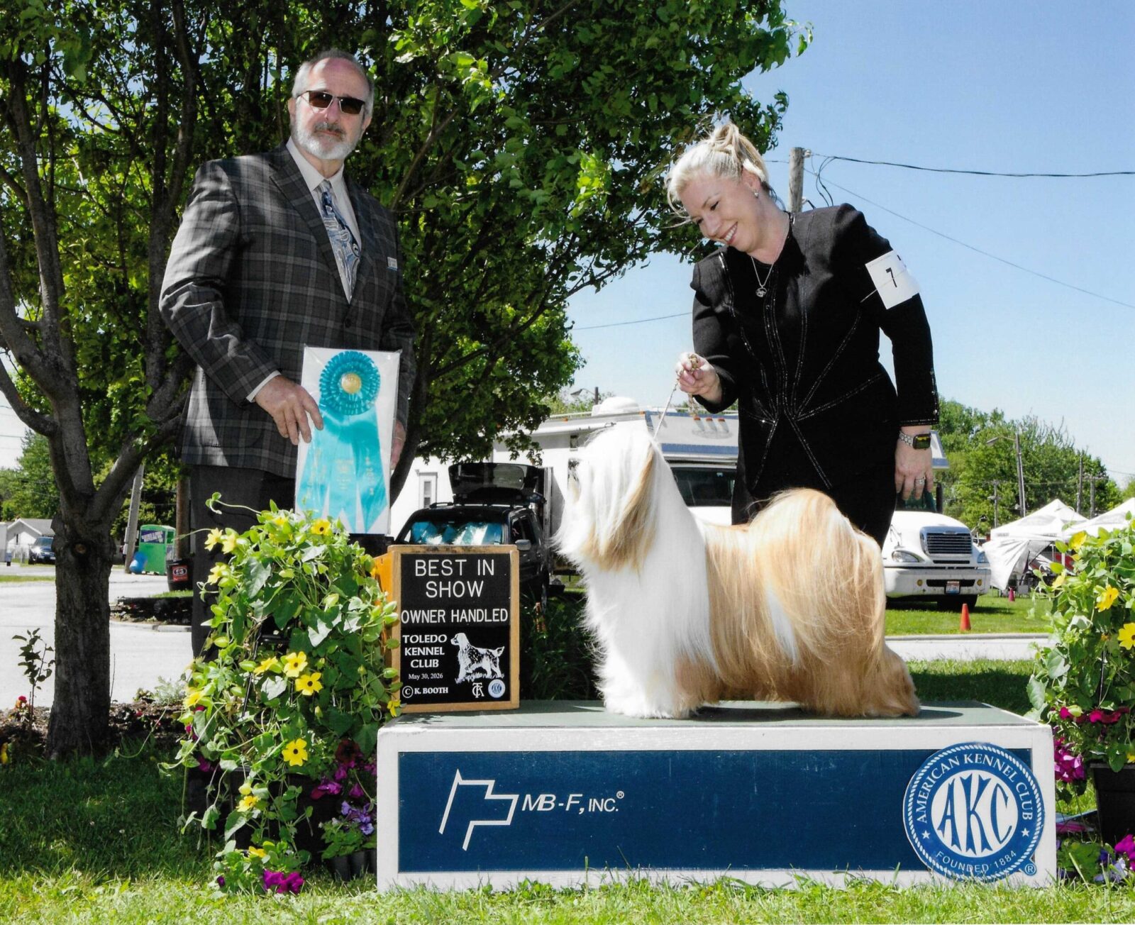 Best in Show Lhasa Apso with handler and judge at dog show.